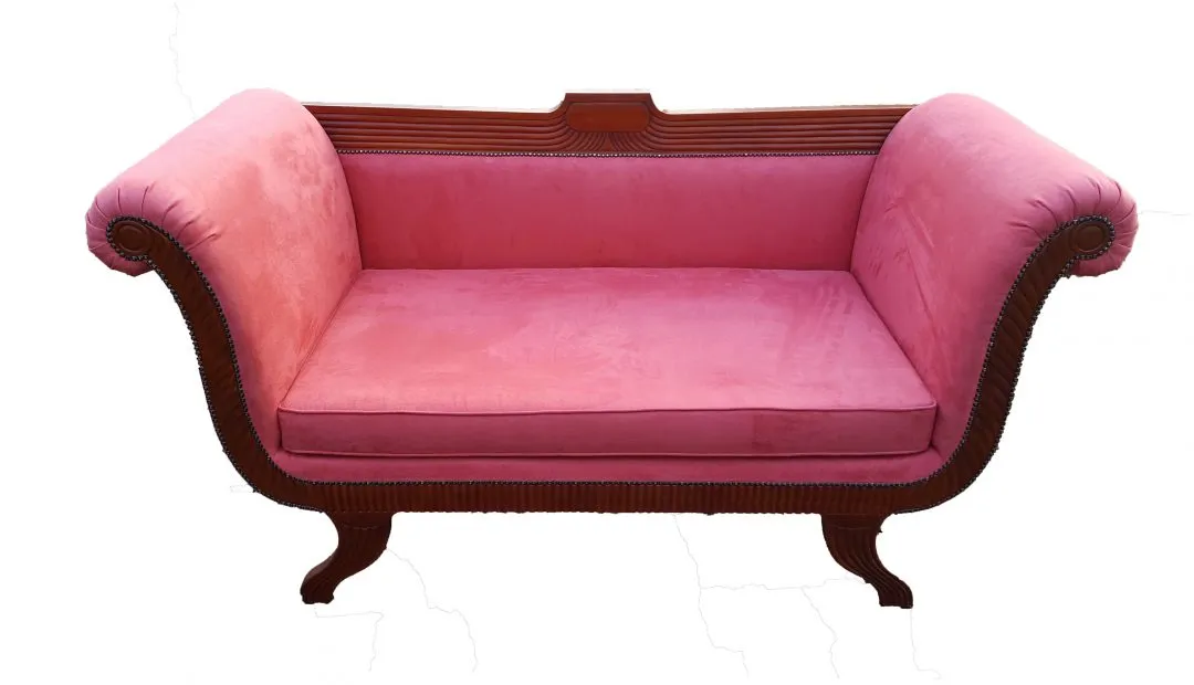 A scroll-arm sofa in pink velvet with a carved mahogany frame